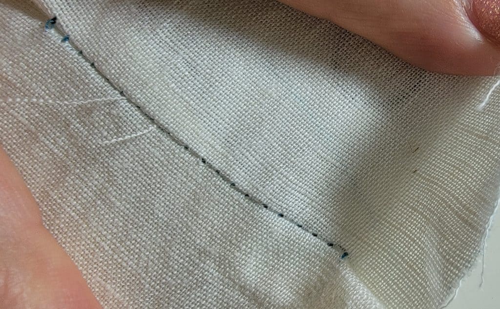 Black and white stitches on white fabric. Good sewing tension - fabric does not pull apart and both color of stitches are visible in the middle.