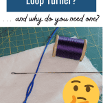 What is a Loop Turner? ... and why do you need one? Picture of a spool of purple thread, blue bodkin, and a loop turner on white fabric follow.